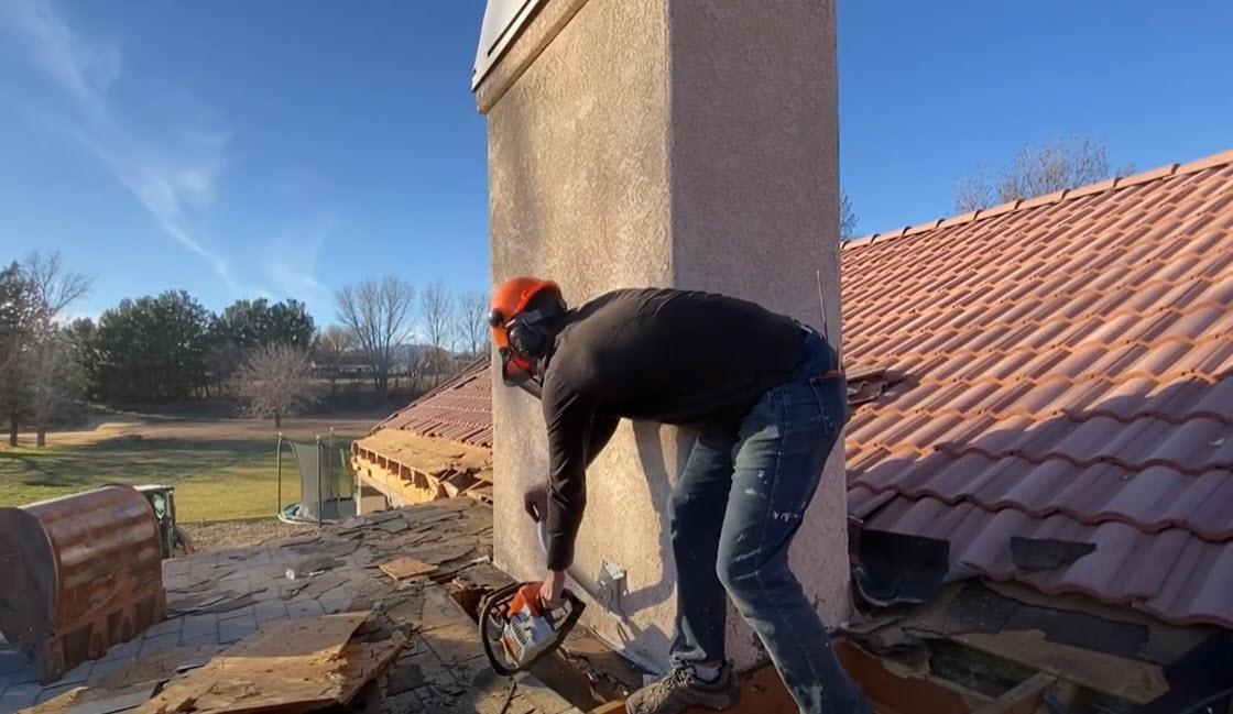 man using chaiinsaw to demo a home